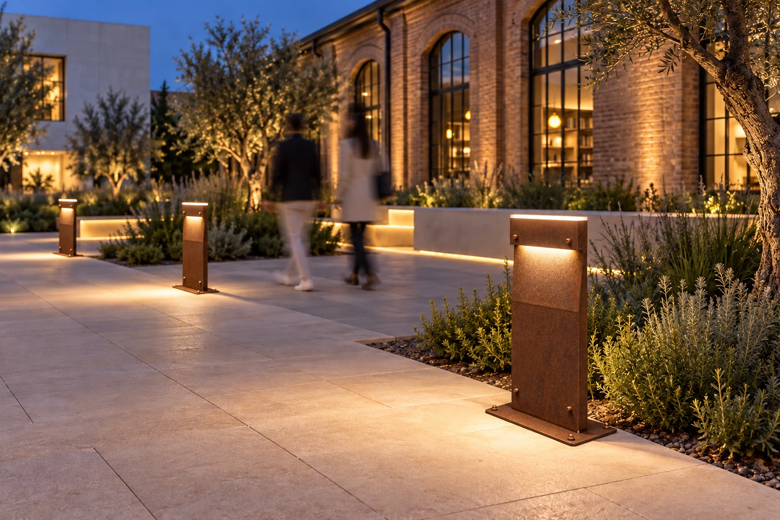 Night concept of a square with DOLMEN base bollards in a proposed corten finish with copper-coloured details, people blurred