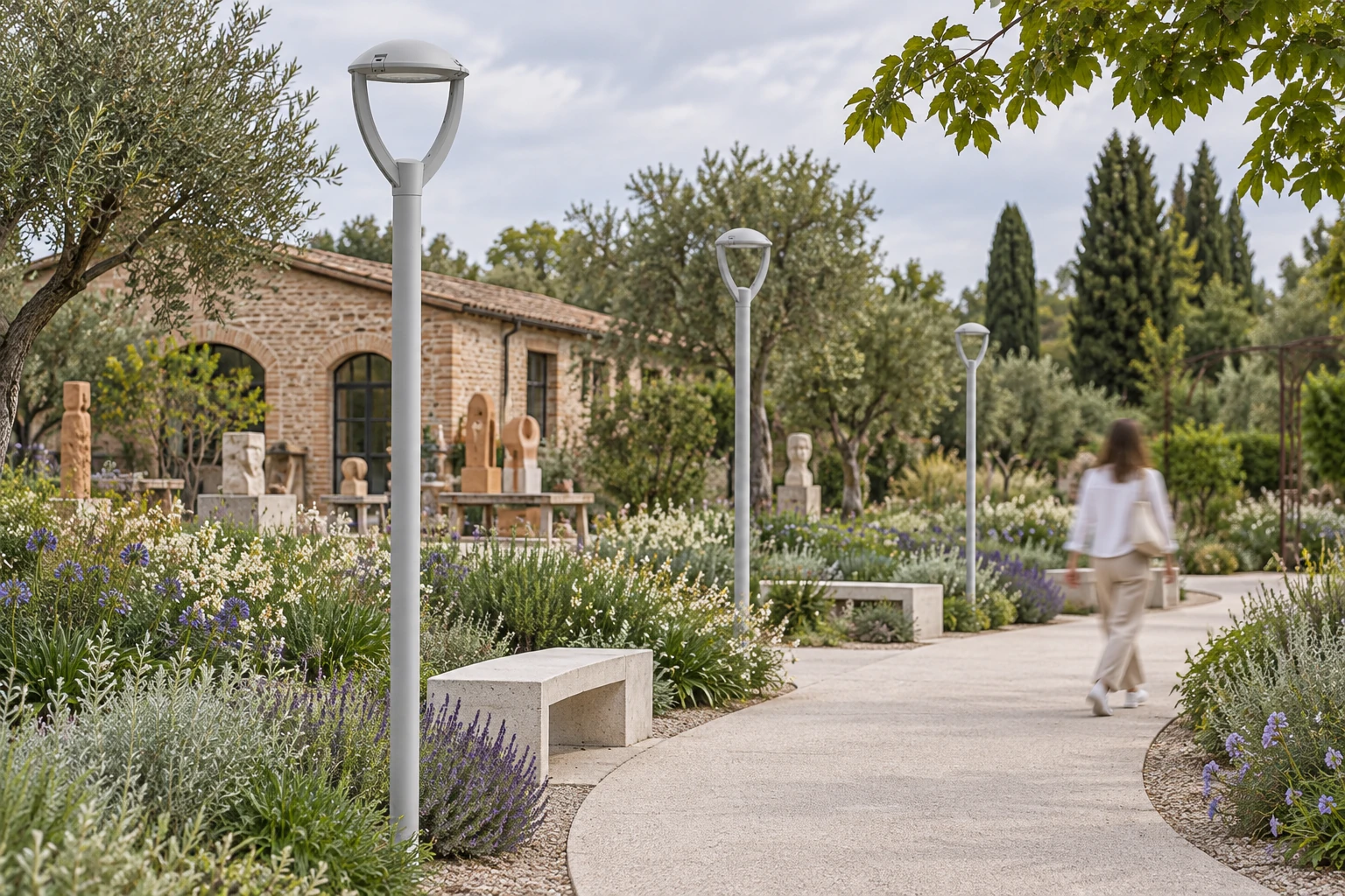 Switched-off NEWTON Small Top Pole in an art garden, with a light-grey cap and two open curved arms. The scene does not establish size or dimensions: revision and measurements must be verified with the technical office; pole height and supports are illustrative.