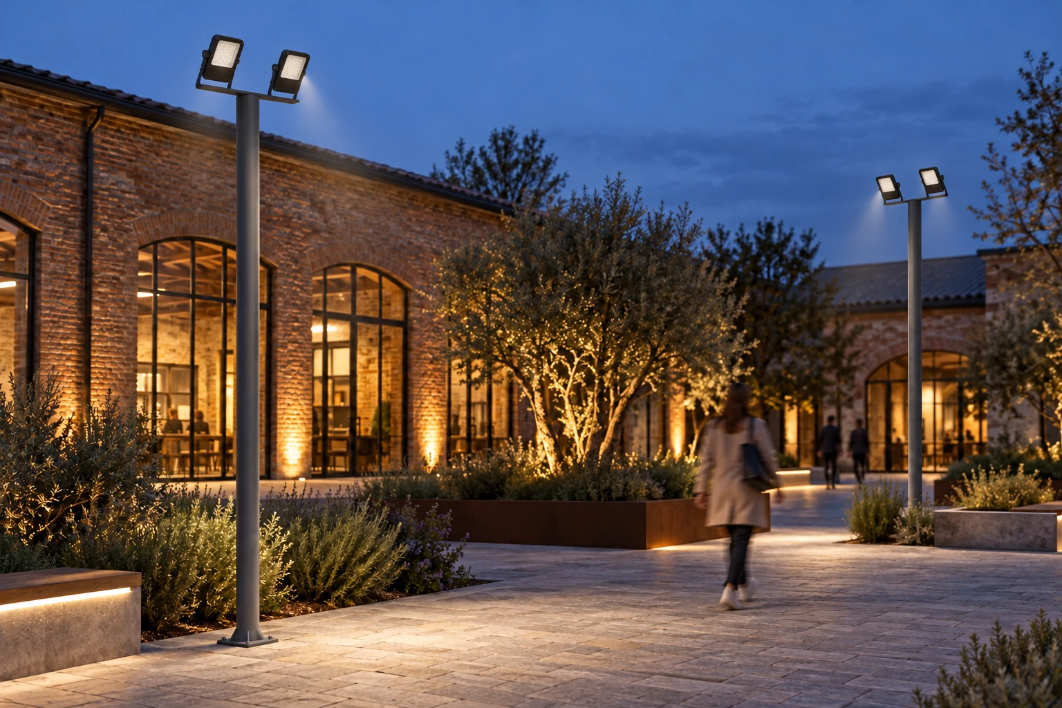 Two Mini luminaires on a pole-top crossbar, with U brackets and optics aimed towards the courtyard. Housing 390 × 310 × 75 mm; pole, arrangement and lighting are illustrative.