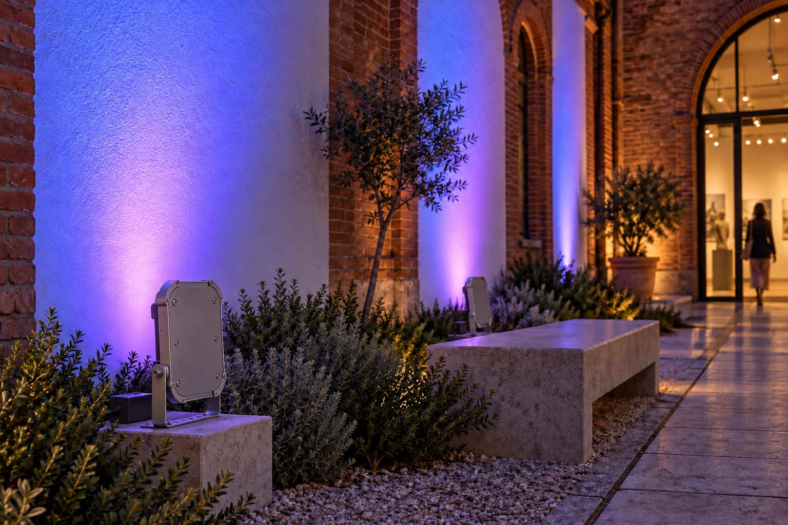 Evening concept with bracket-mounted floodlights aimed towards the wall. Coloured lighting is illustrative; the scene identifies no current-range code, DMX control or measured performance.